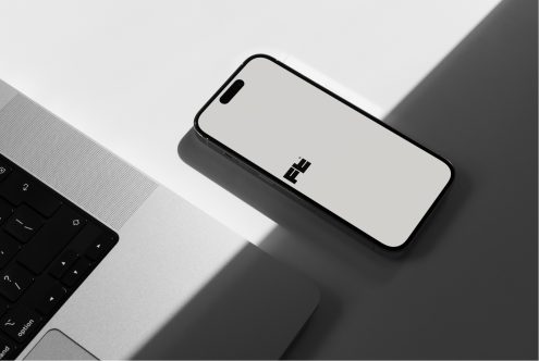 Phone mockup next to laptop keyboard in bright workspace setup