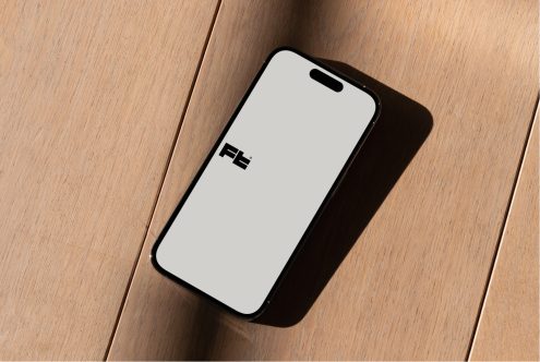 Overhead shot of iPhone on wooden surface casting sharp shadow with FE logo