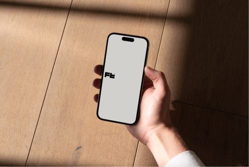 iPhone lying flat on wood flooring showing white display with FE branding visible