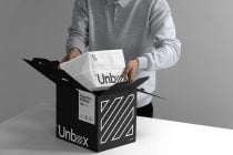 Person pulling out white nested boxes from black patterned shipping carton