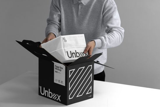 Person holding a white mockup box coming out of a stylish black packaging, ideal for product presentation and branding designs.