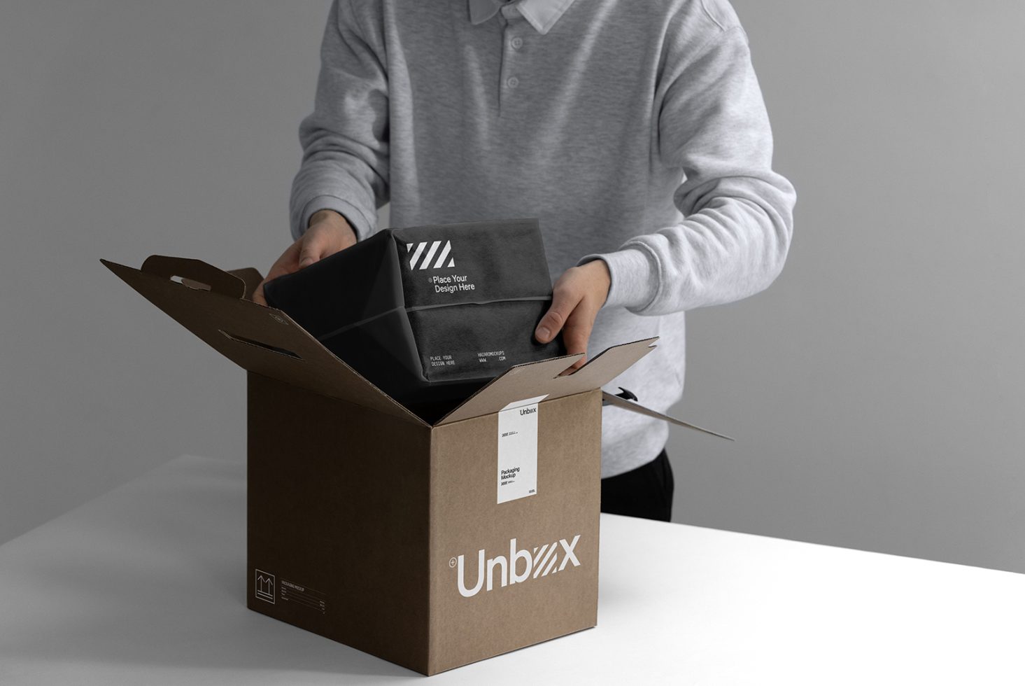 Person unpacking a stylish black box from a cardboard package, ideal for mockup presentations and packaging design.