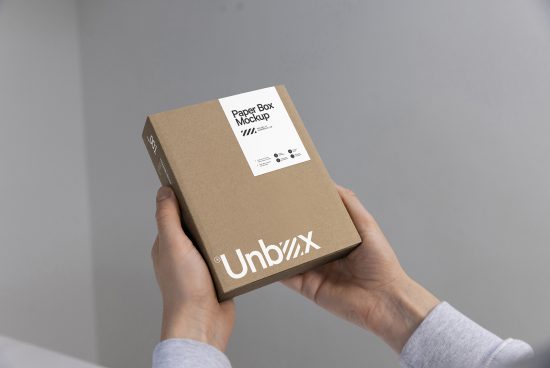 Person holding a cardboard box mockup with a label design, ideal for packaging, branding, and graphic design presentations.