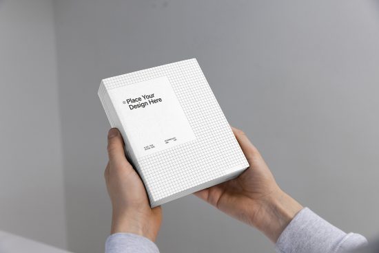 Hands holding a book mockup with a replaceable cover design against a grey background, perfect for presentations and portfolios.
