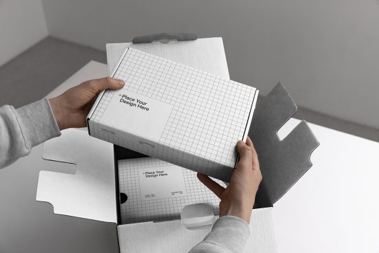 Hands holding a grid-lined box packaging mockup with customizable design space, ideal for presentations and branding projects.