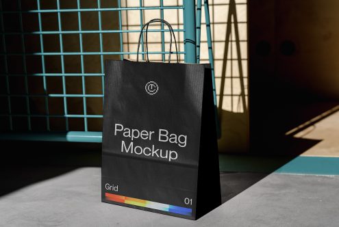 Black paper bag mockup with rainbow stripe on teal grid surface backdrop