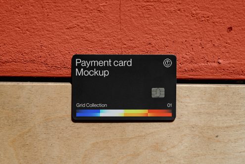 Black payment card with colorful gradient stripe on rust, tan surface