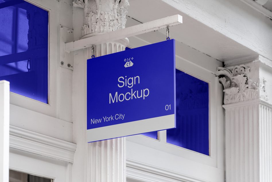 Bright blue hanging sign with white text mounted on ornate white ceiling brackets