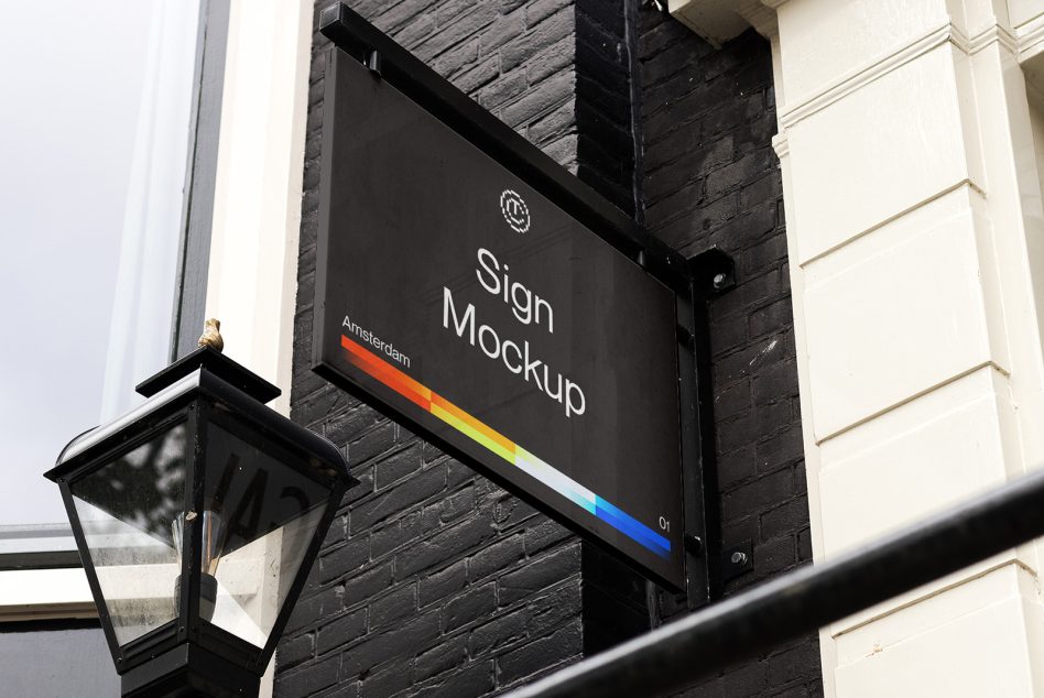 Black hanging sign with rainbow stripe detail on brick storefront wall