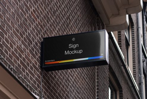 Horizontal black sign on brick wall showing rainbow color gradient stripe
