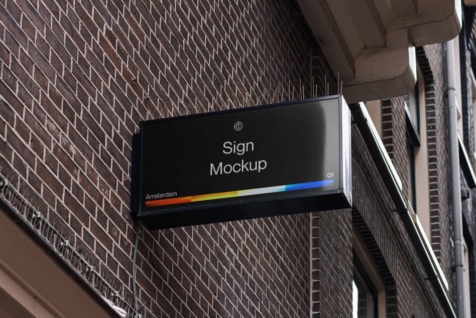 Horizontal black sign on brick wall showing rainbow color gradient stripe