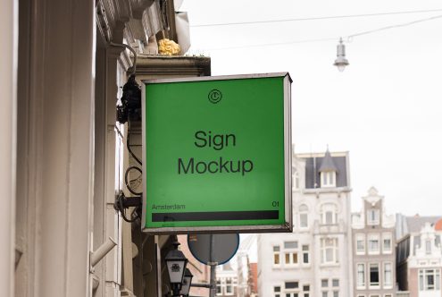 Bright green storefront sign mounted on historic Amsterdam building facade with blurred street behind