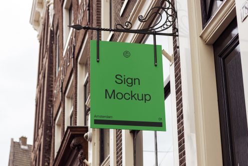 Bright green storefront sign hanging from ornate black bracket on brick building facade