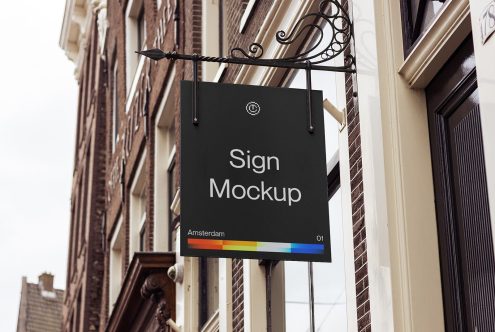 Black storefront sign hanging from ornate bracket on brick building facade