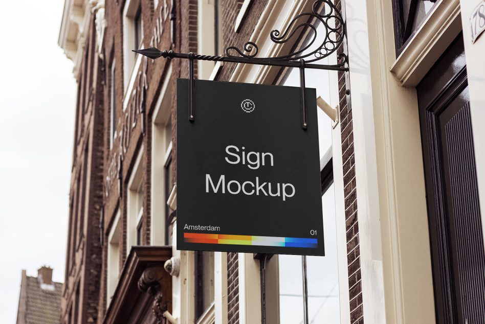 Black storefront sign hanging from ornate bracket on brick building facade