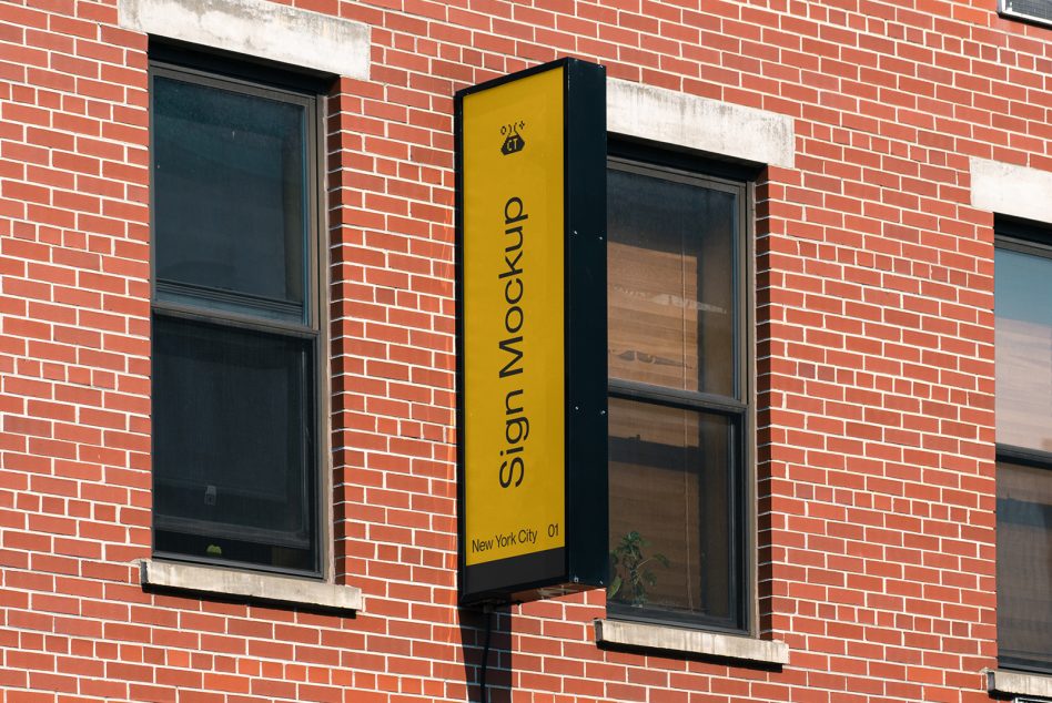 Yellow vertical pole sign on red brick wall between two dark window frames