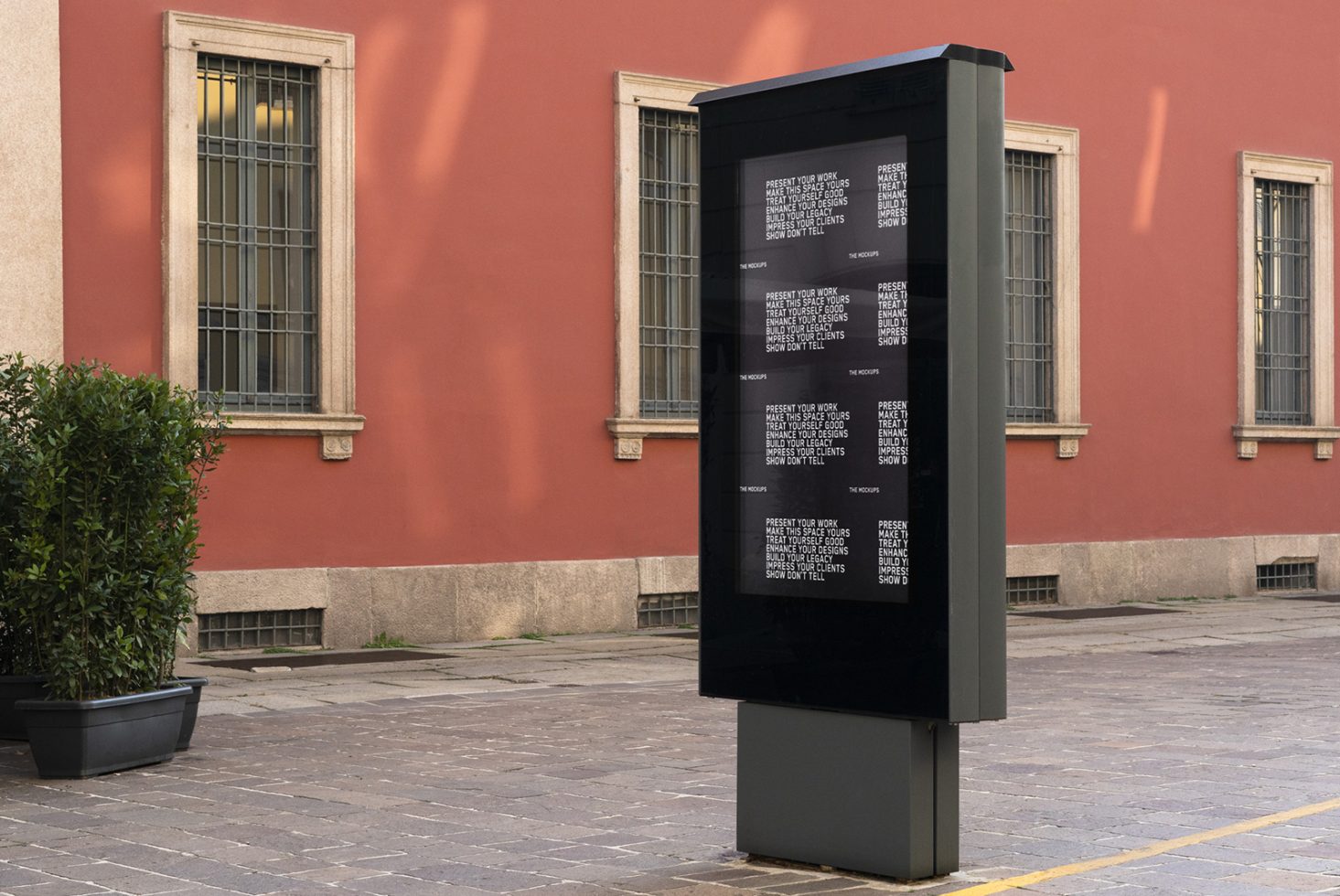 Outdoor advertising mockup with urban digital kiosk for showcasing branding designs on a terracotta building background with greenery.