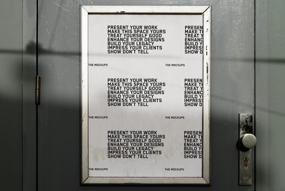White framed poster on worn metal door with industrial concrete wall