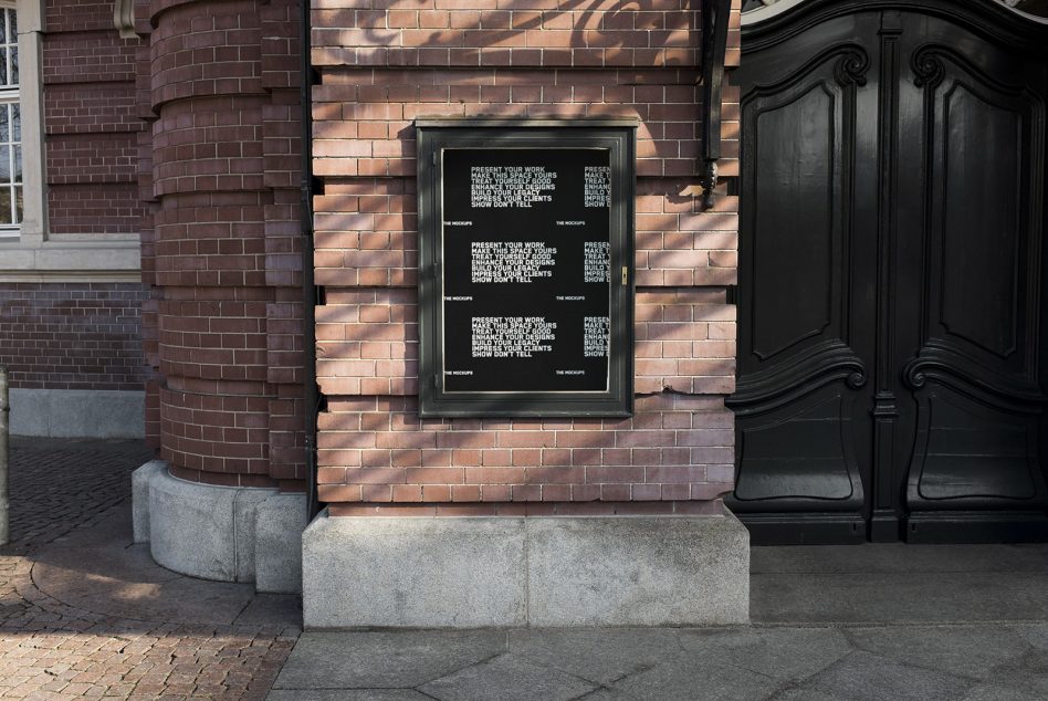 Outdoor poster mockup on a brick wall beside a wooden door, ideal for presenting design work, branding, and poster graphics to clients.