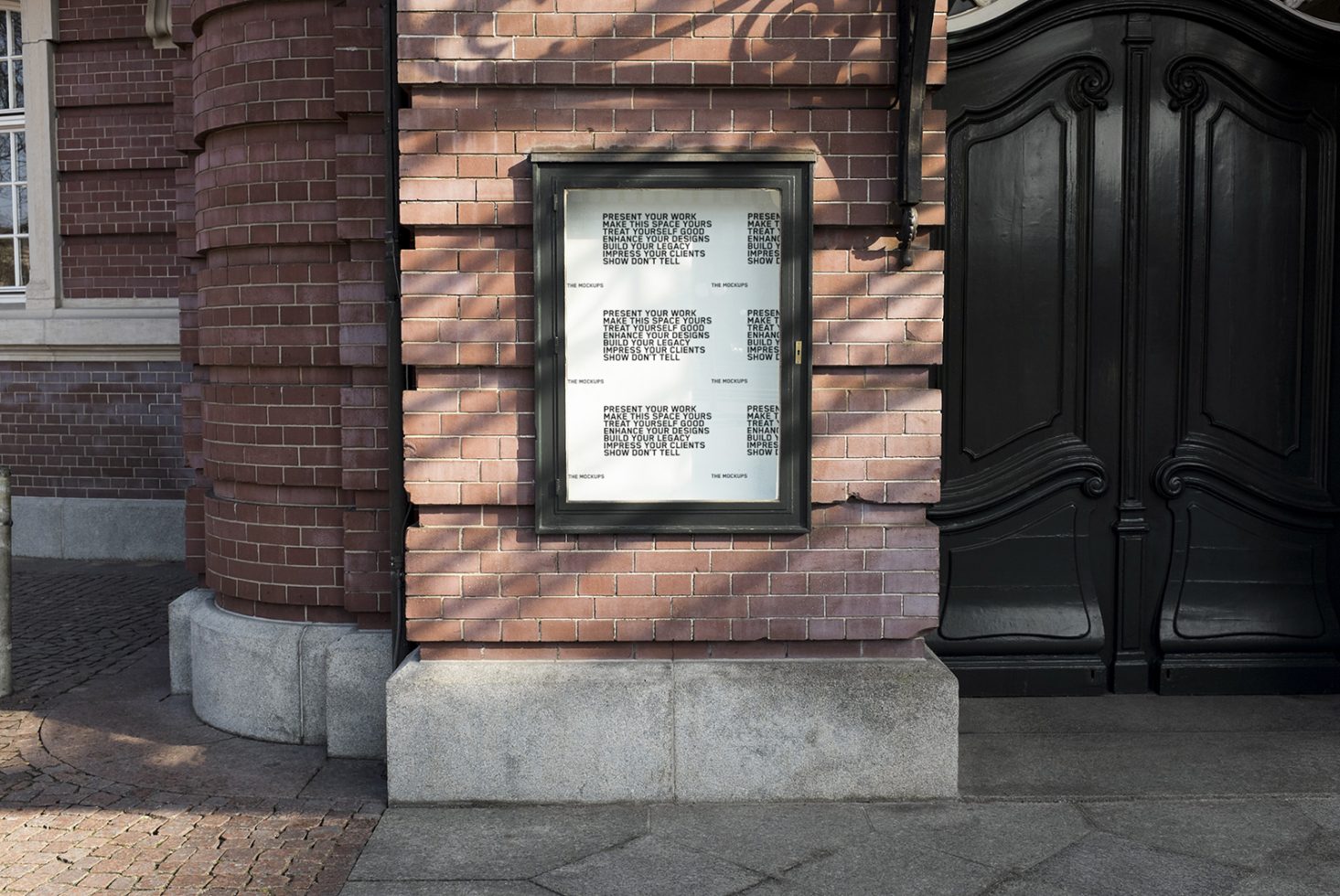 Urban poster mockup on brick wall by a stylish black door, ideal for presenting design work and fonts in a realistic outdoor setting.