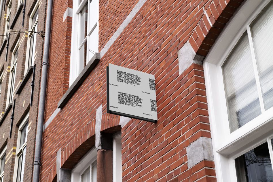 Horizontal sign mockup mounted on red brick building between windows