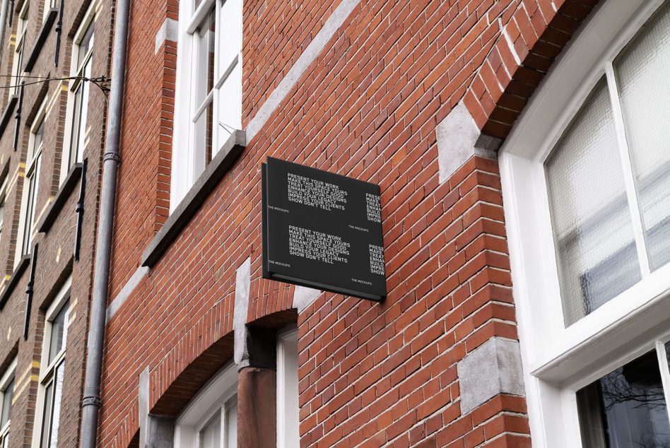 Black horizontal sign mounted on red brick building with white text