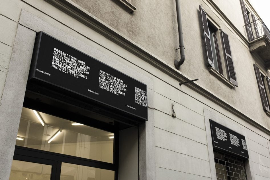 Storefront with illuminated window, black horizontal signage above entrance on white wall