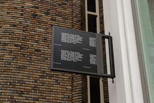 Outdoor advertising mockup hanging on brick wall exterior, tailored for design presentations and portfolio displays.