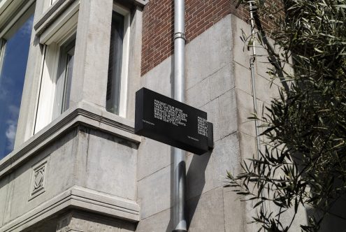 Black outdoor signage mockup on building facade with clear text, suitable for designers to display their branding work in a real-world scenario.