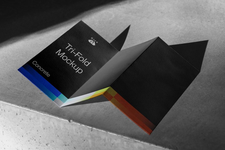 Tri-fold brochure mockup with black cover, colorful gradient spine on concrete