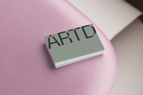 Soft sage green business cards fanned on pink circular platform