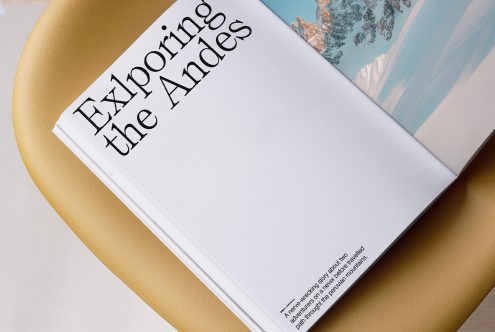 Open book with serif typography on gold circle, mountain landscape photo peeking from pages