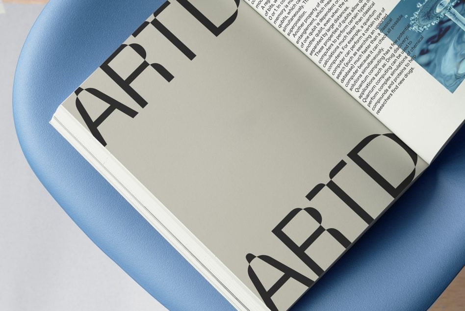 Open magazine on blue fabric showing bold sans serif typography with text pages