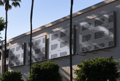 Outdoor advertising mockup with illuminated posters on building facade surrounded by palm trees, ideal for showcasing design templates.