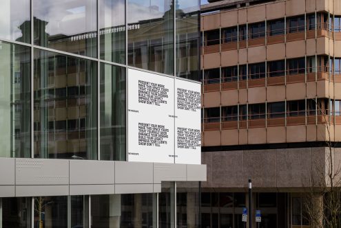 Urban poster mockup on glass building for branding and advertising designs with reflections of surrounding architecture.