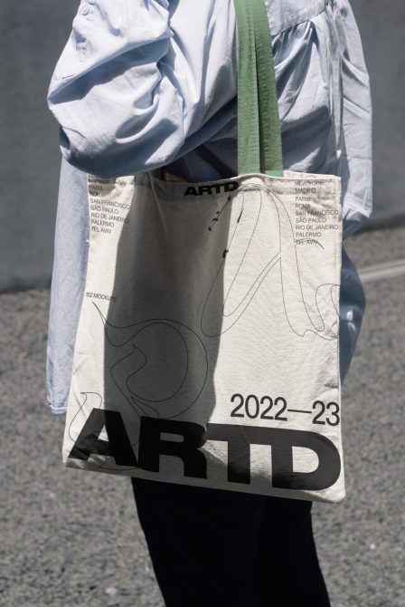 Canvas tote bag mockup with minimalist line art, city names, bold typography on cream fabric