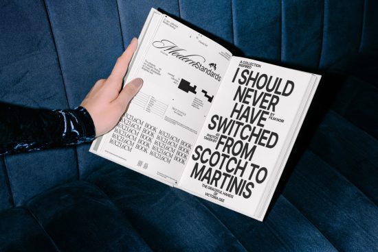 Hand holding open magazine mockup on blue couch, displaying bold font design and page layout, ideal for templates, graphics, and fonts presentations.