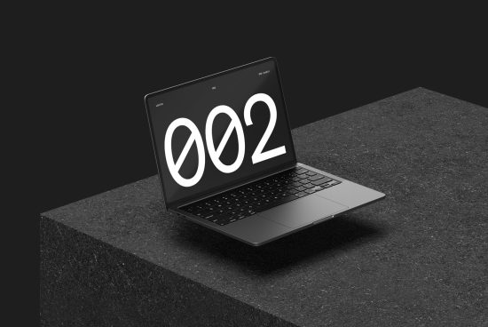 Laptop on dark textured surface displaying large numeral design, ideal for graphic design mockups, minimalist presentation.