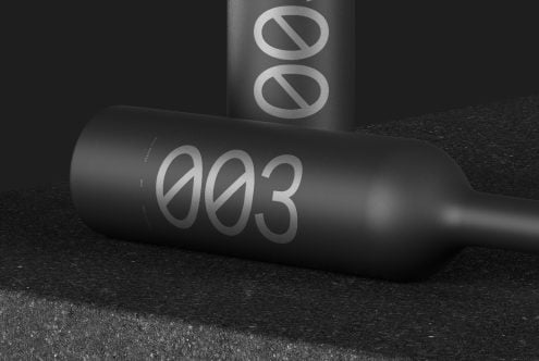 Elegant black bottle mockup with reflective typography design on dark textured background, ideal for showcasing packaging and branding.