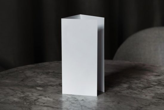 Blank tri-fold brochure mockup on a marble table with a dark backdrop for realistic presentation, graphic design assets.