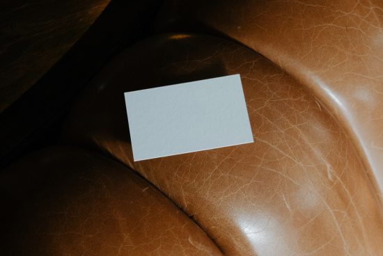 Blank business card mockup on a textured brown leather chair for graphic design and branding presentations.