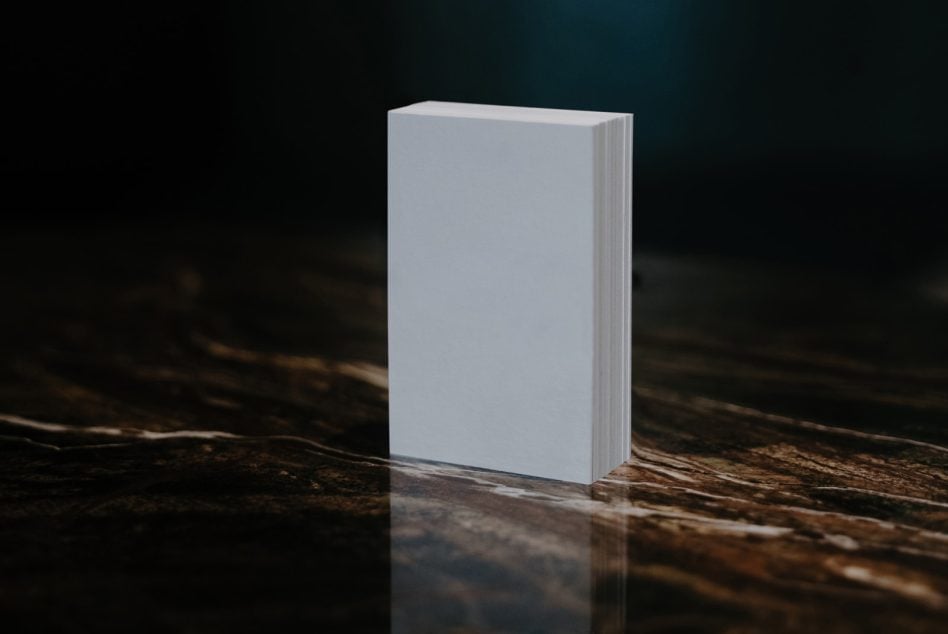 Blank hardcover book mockup on textured wood surface with moody lighting