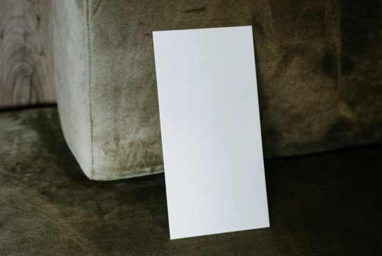 Blank vertical paper mockup leaning against a textured couch, ideal for presentation templates and poster design displays.
