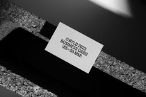 Single white business card tilted on concrete beam with minimalist layout