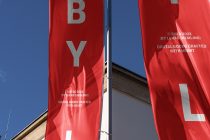Red flag mockup waving on elegant stone building with silver lettering