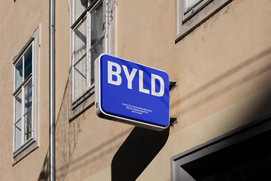 Blue store signboard mockup with elegant sans-serif font mounted on a beige wall, clear sky background, shadows detail, ideal for branding presentation.