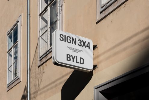 Outdoor sign mockup on a building wall in sunlight, ideal for presenting logo and branding designs to clients, relevant for designers and agencies.