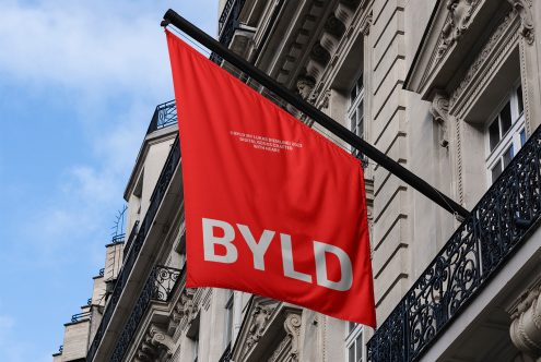 Red flag mockup with bold white typography hanging on a building, showcasing branding design and urban presentation for graphic designers.