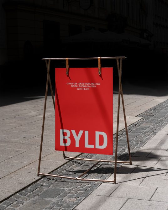 Urban street sandwich board mockup with bold red poster design, standing on pavement, showcasing modern fonts and branding in natural light.