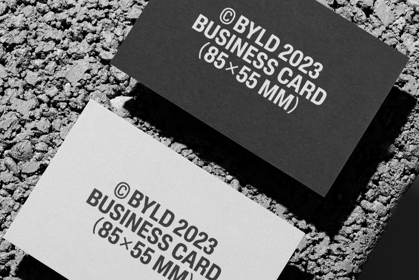 Black and white business cards with minimalistic design lying on a textured surface, ideal for mockup and graphic design templates.